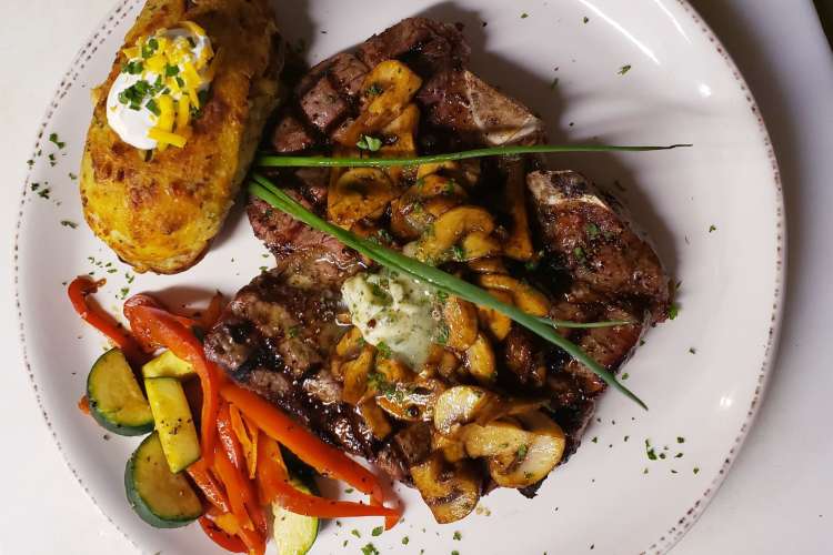 a juicy steak, baked potato and sauteed vegetables