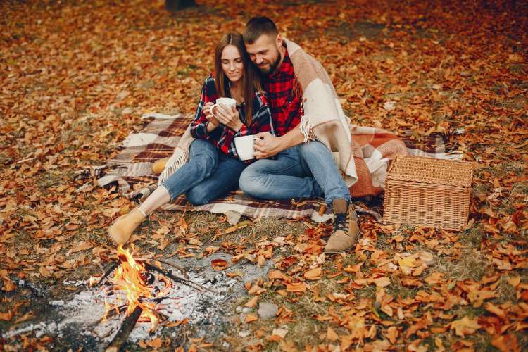 a couple having a picnic together near the fall leaves