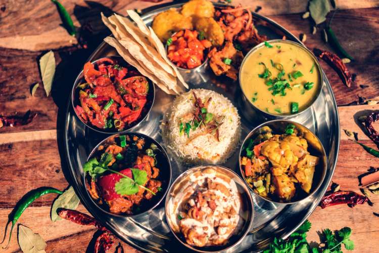 Indian thali platter with a variety of dishes ranged around rice 