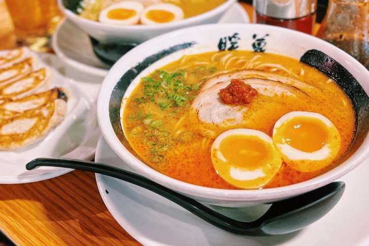 a bowl of ramen with red soup and an egg