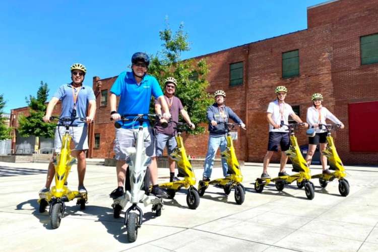 a group of people on three-wheel scooters smile for the camera