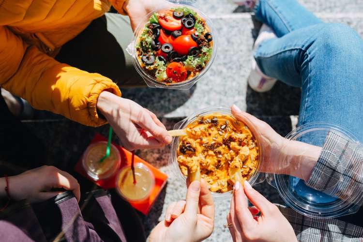 a group of people share dips and chips together outside