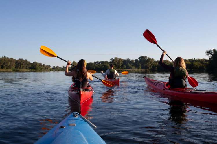 people kayaking on a lake with a hilly, wooded background