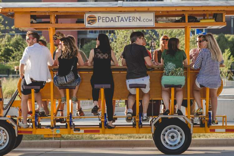 A group of people sit around the bar of a pedal tavern.