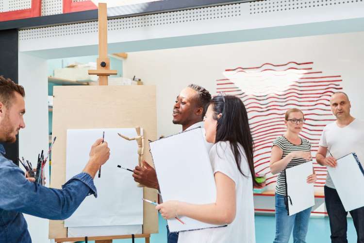 an instructor gives feedback to adult students in a painting class