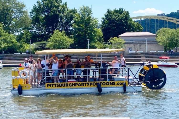 a pontoon in the water filled with smiling people