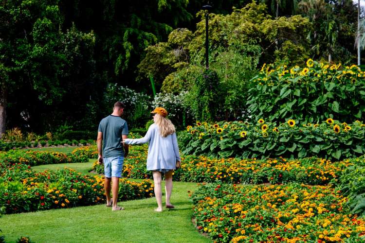 a couple walks together through a colorful botanical garden