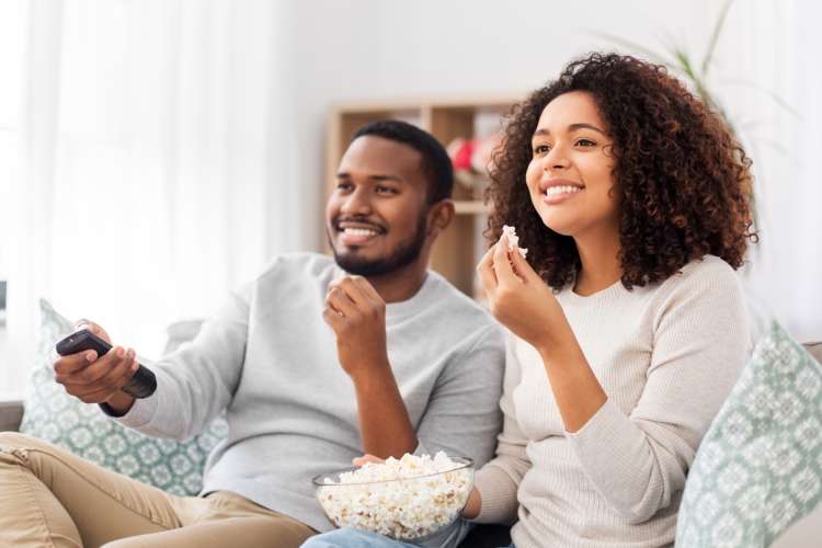 young couple watching tv on the couch with popcorn