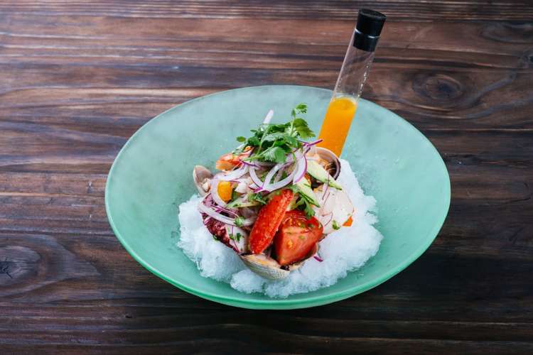 a plate of artfully arranged rice and seafood with a vial of sauce