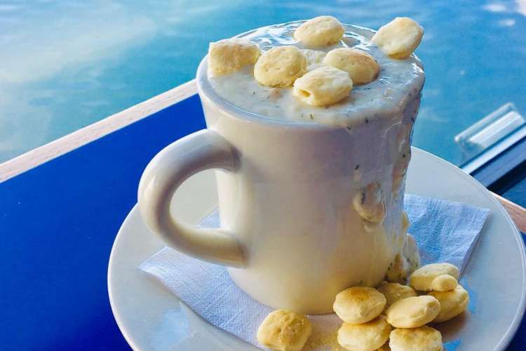 an overflowing mug of clam chowder with croutons