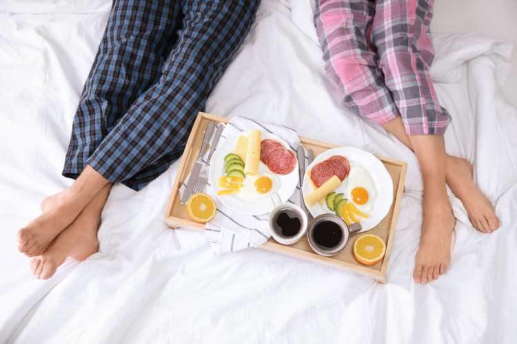 Breakfast in bed is a romantic first-anniversary date idea.