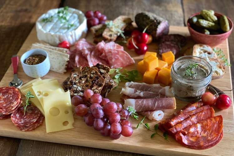 a charcuterie board with meats, fruits, cheeses, and crackers