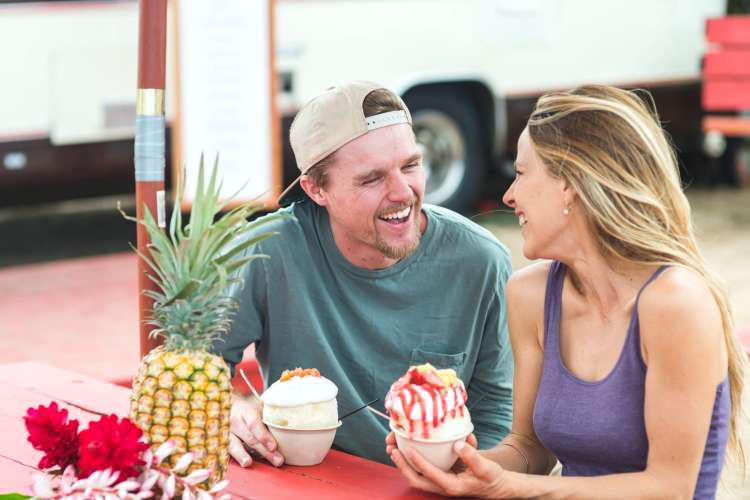 a couple laughing and chatting while eating ice cream sundaes