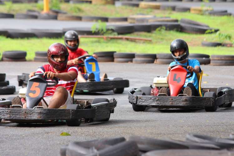 three helmeted riders race go-karts