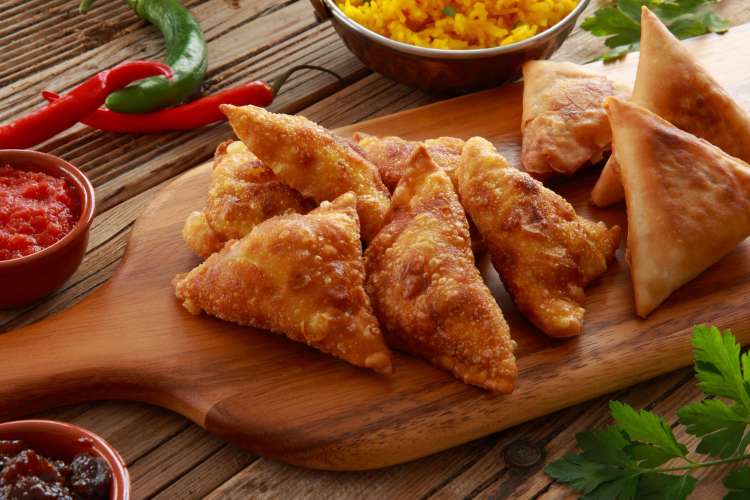 fried, triangular samosas with garnishes and sauce