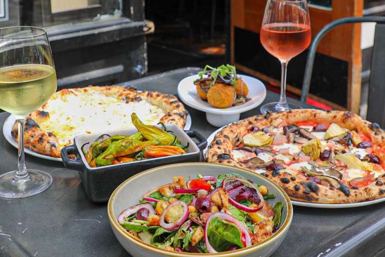 pizza, salad, vegetables and wine on a set table