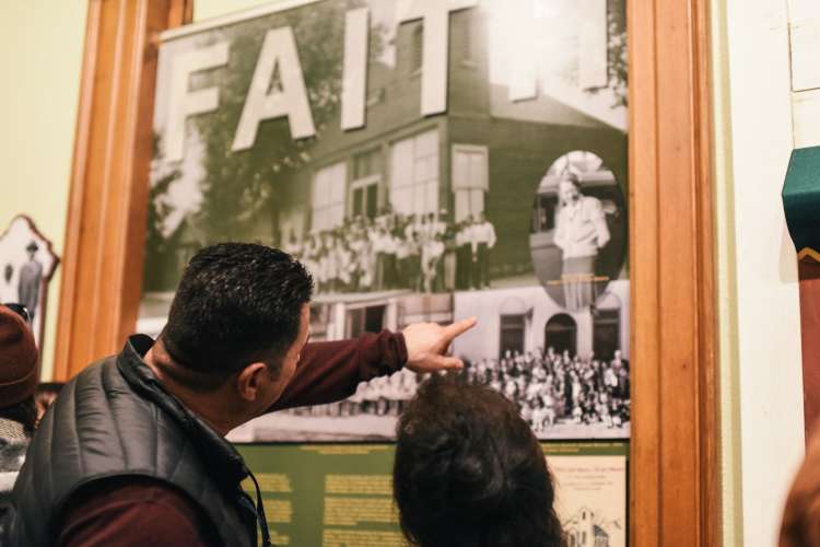 two people discussing a black and white photo exhibit titled Faith