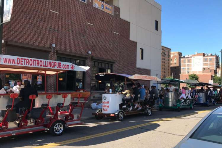 a row of rolling pubs filled with customers along a side street