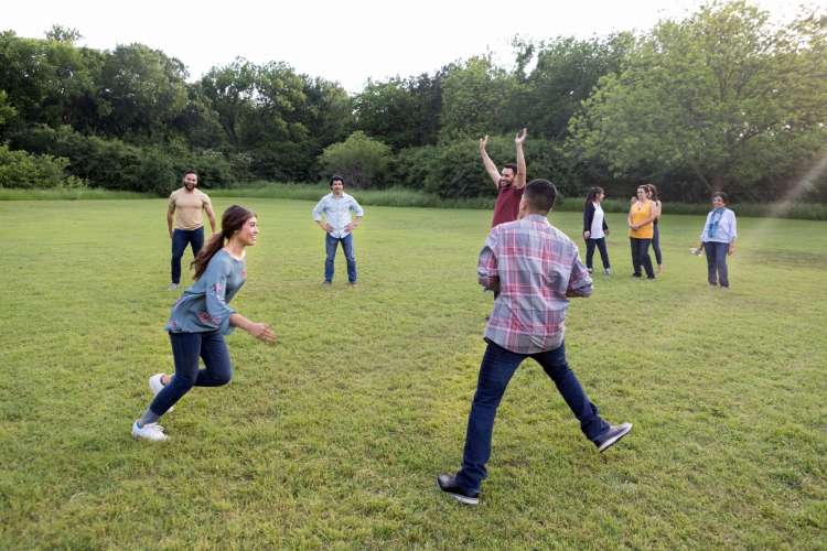 a group of adults plays a ball game while others look on and chat