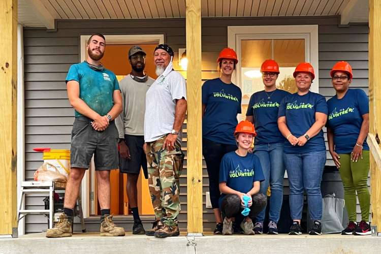 a group of Habitat for Humanity volunteers smiles from a front porch