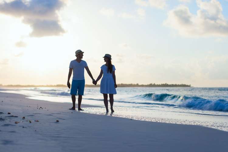 a couple strolling along the beach hand in hand