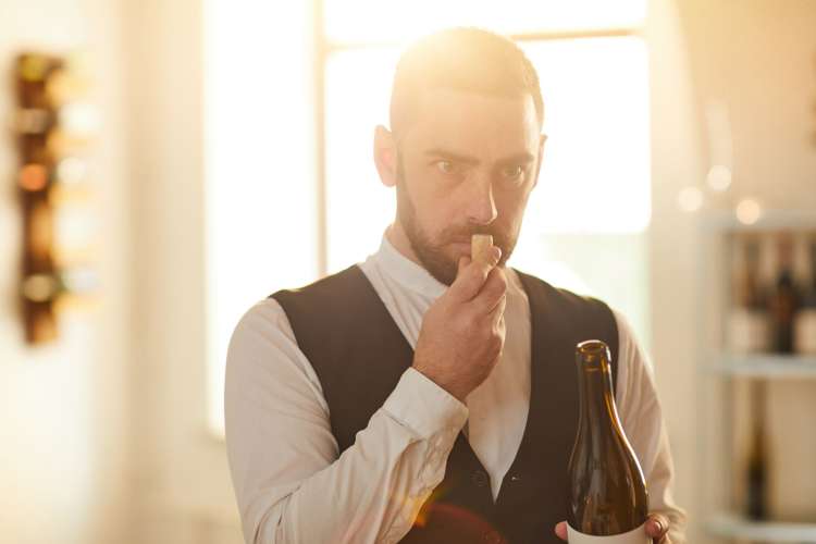 A sommelier smelling a wine cork and looking thoughtful