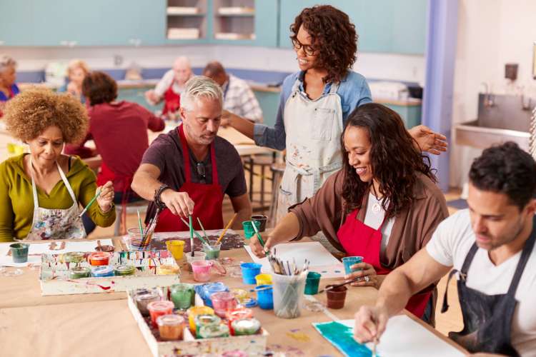 three people getting a painting lesson from an instructor