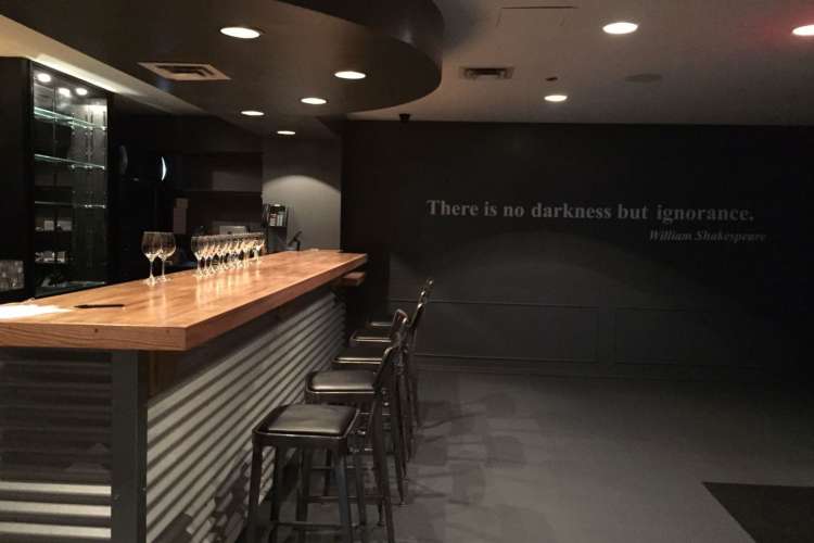 an elegant dim bar and seating area with a quote about darkness on the back wall