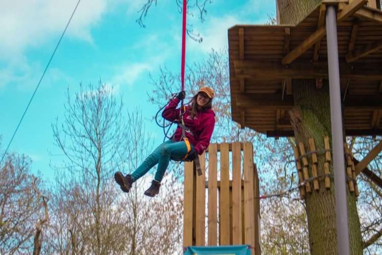 a smiling woman up on a zip line 