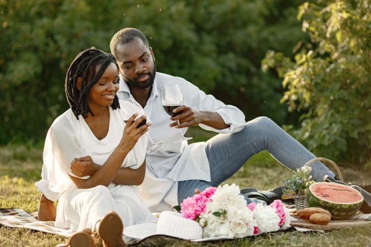 A couple drinking wine during a tranquil picnic — a great one-year anniversary date idea