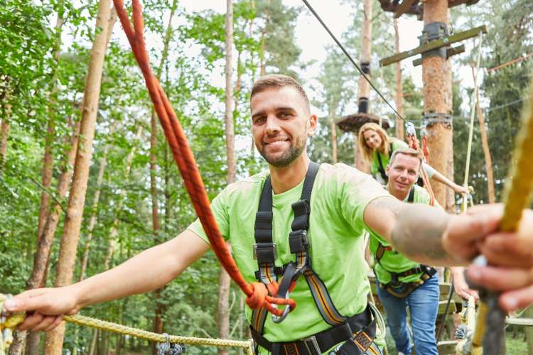 a man in a green shirt doing a ropes course