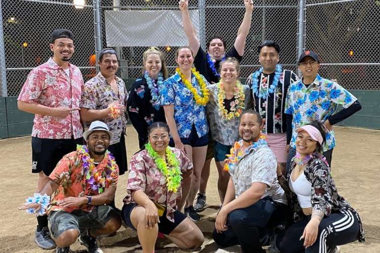 a team in Hawaiian shirts poses together on a softball field