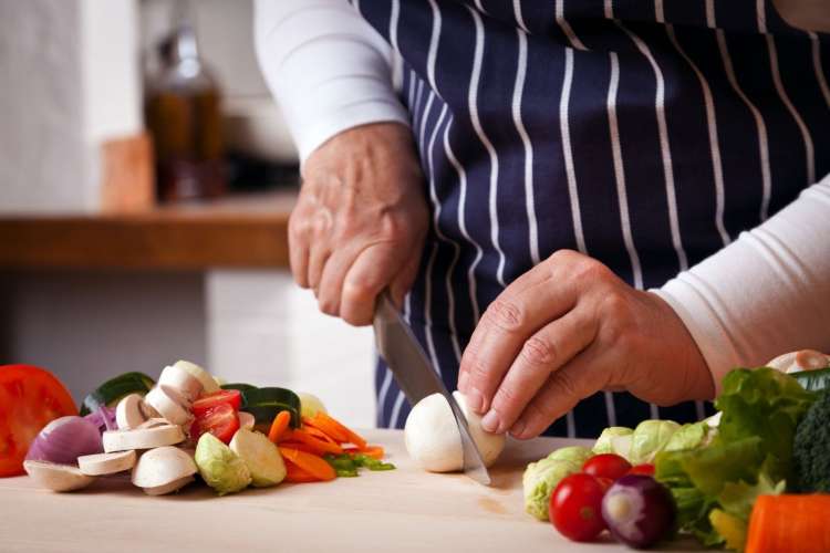 chef chopping produce with a chef's knife 