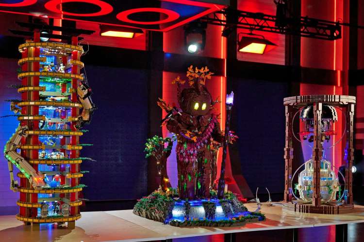 three large figures made of Legos sit on a table in a neon-lit room