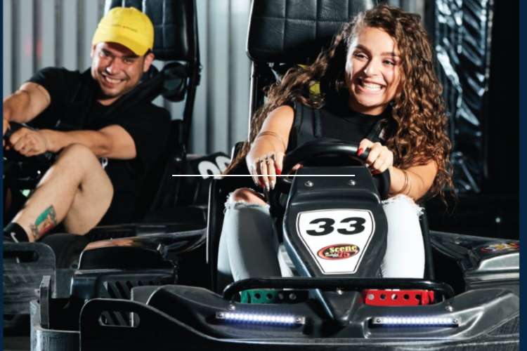 a smiling man and a woman race go-karts 