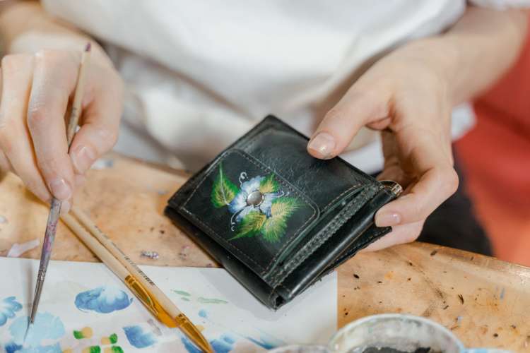 a woman painting on an old wallet