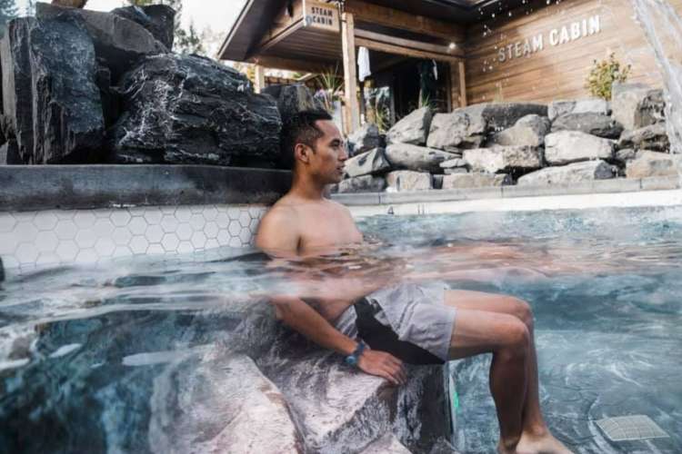 a man partly submerged in hot water in an outdoor hot springs