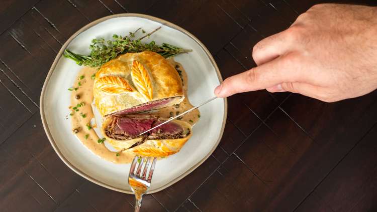 a knife slicing into Beef Wellington