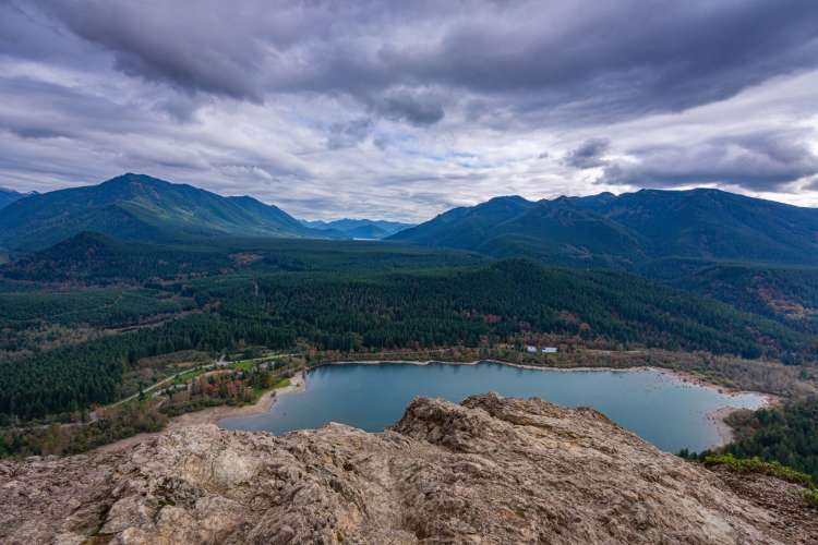 gray clouds and mountains in front of a blue lake