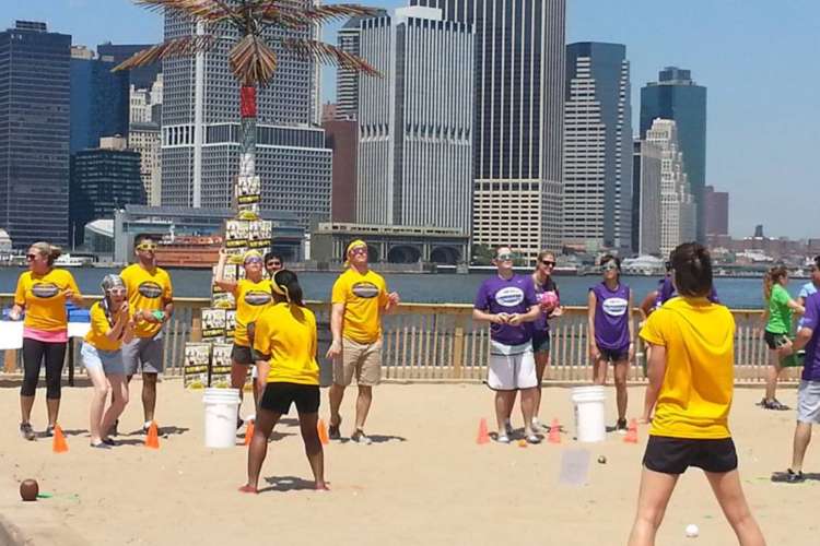 a group of people in yellow shirts playing volleyball in the sun