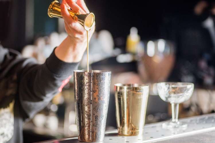 bartender pouring a cocktail during a mixology class