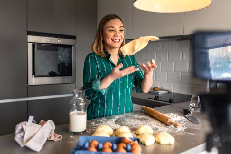 woman flipping pizza dough during an online cooking class