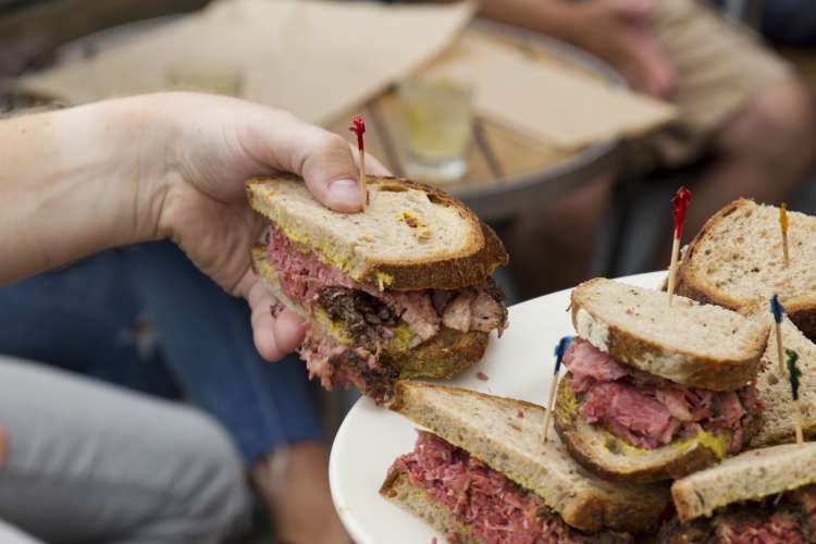 folks enjoying pastrami sandwiches during a food tour