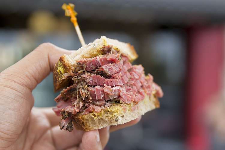 A hand holding a meat sandwich