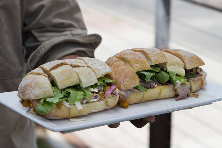 guide handing out sandwich samples on a food tour