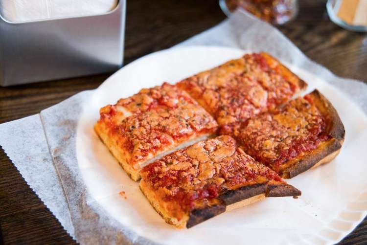 squares of deep dish pizza on a paper plate