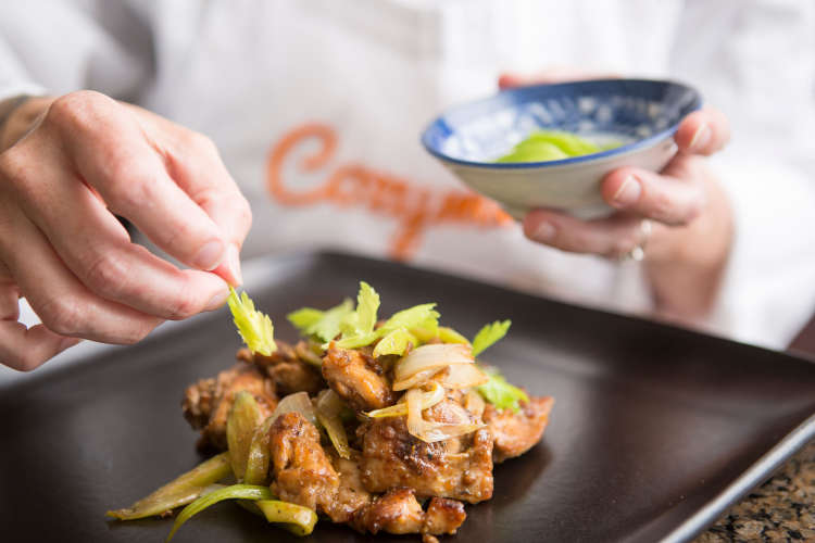 chef with cozymeal plating a chicken dish