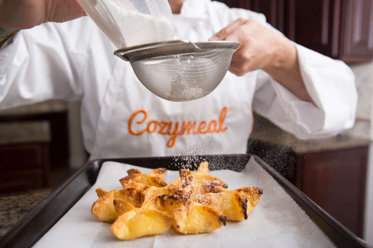 chef sprinkling powdered sugar over fried wonton shells