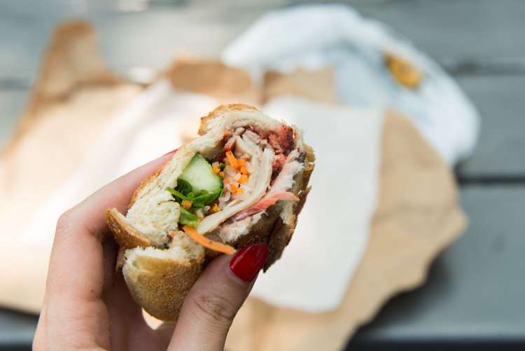 woman's hand holding a sandwich with picked vegetables