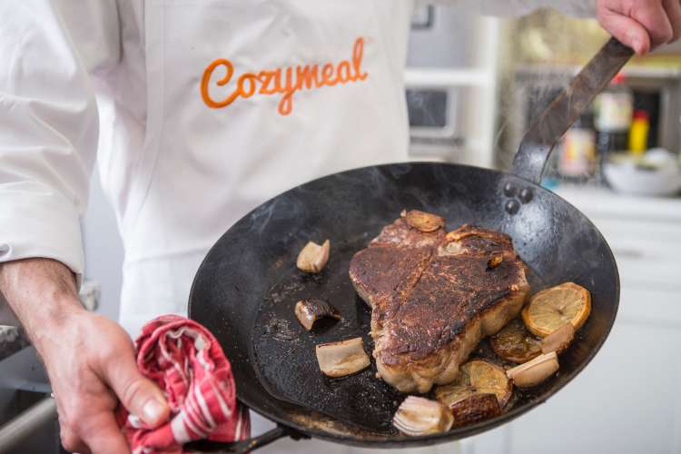 private chef holding a pan with steak